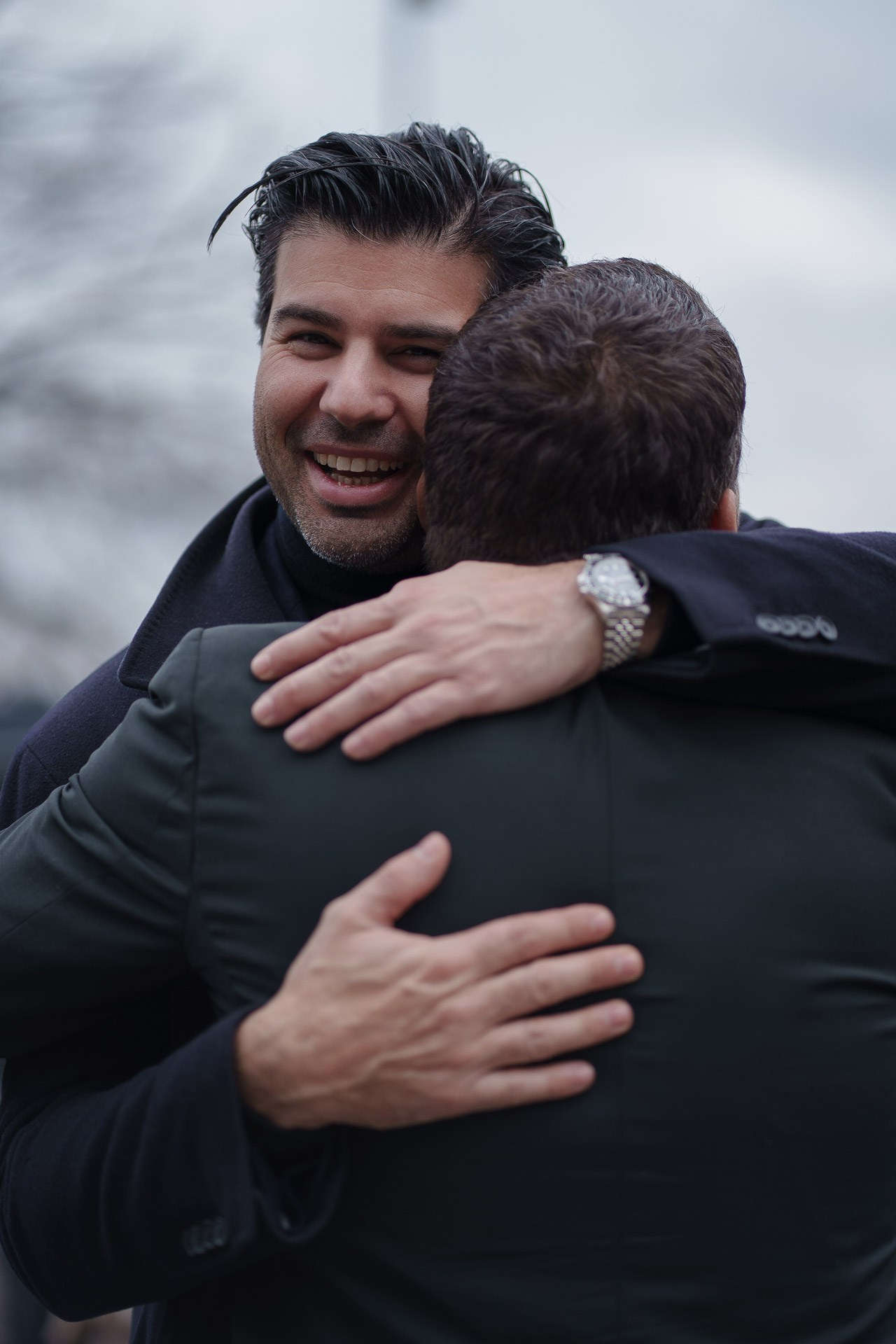 Men greeting and hugging each other during Pitti Uomo 109 Florence