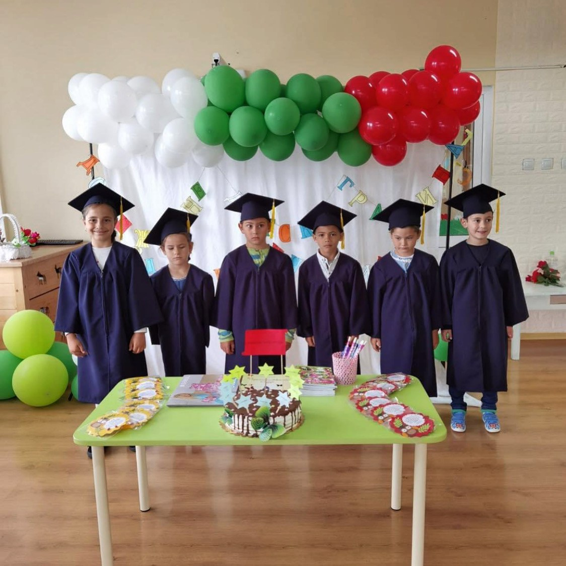 Деца с комплекти детски тоги и шапки за завършване на детска градина в тъмно син цвят