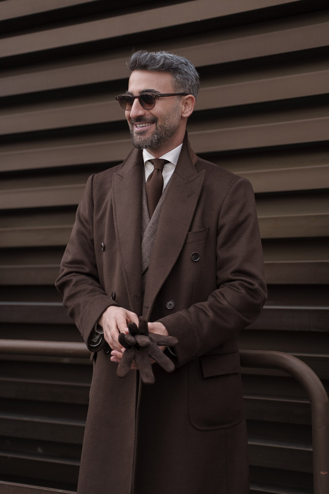 Smiling man in brown coat wearing sunglasses at Pitti Uomo 109 Florence