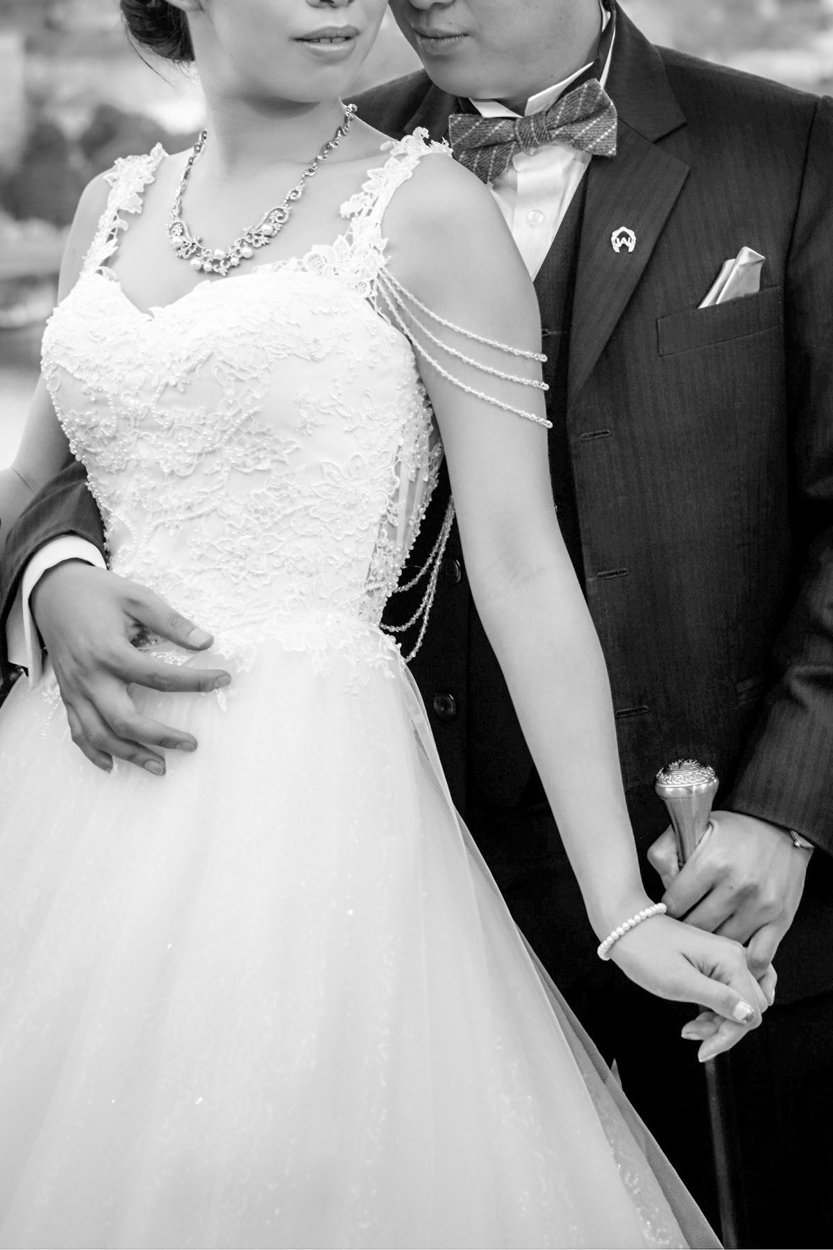 A close-up photo of a stylishly dressed bride and groom holding a cane.