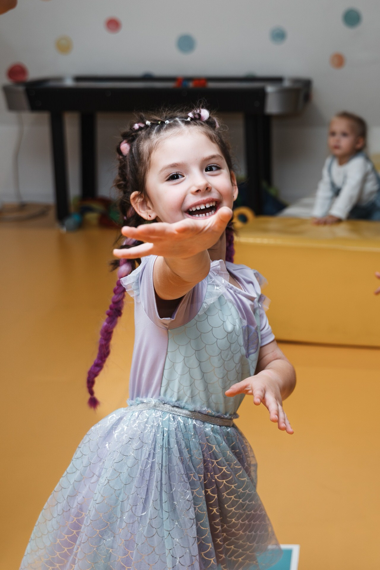 Devojčica sa kikicama u haljini gleda u fotoaparat