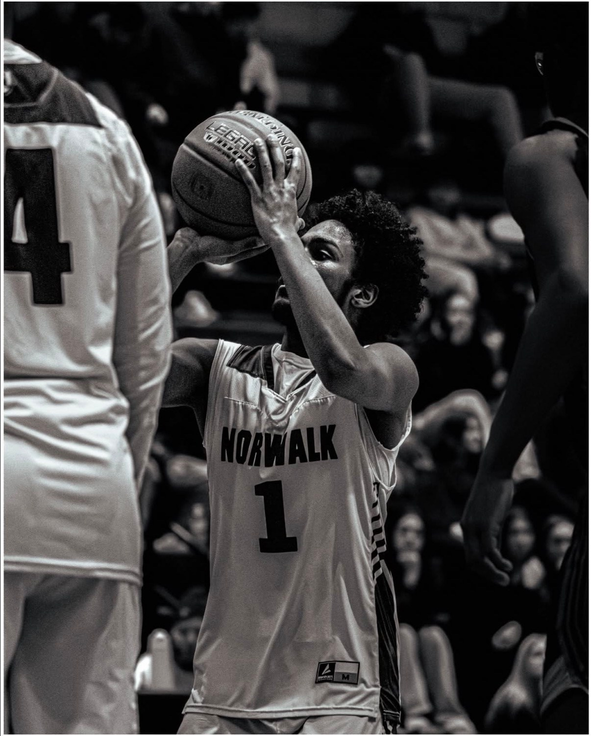 Black and white close-up of a basketball player holding the ball with a focused expression during a free throw. 