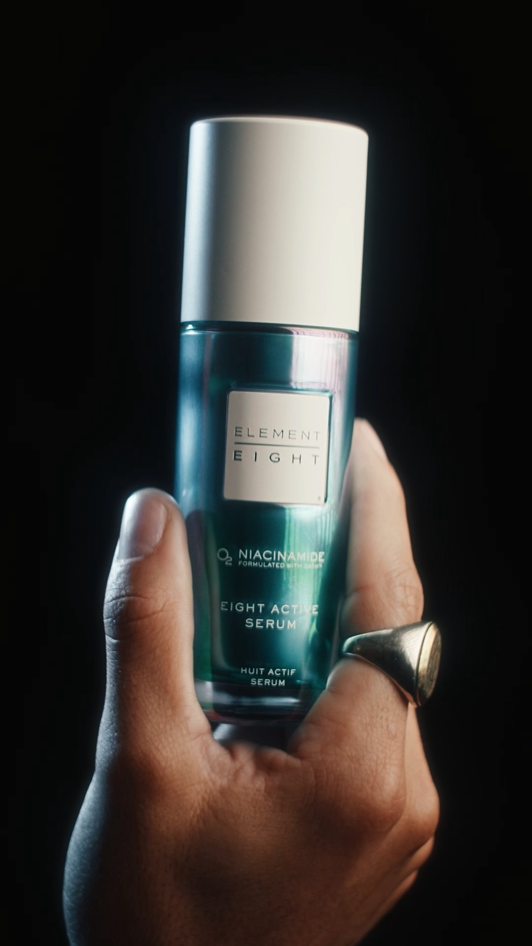 Luxury skincare product bottle held against a dark background, highlighting elegant packaging design.