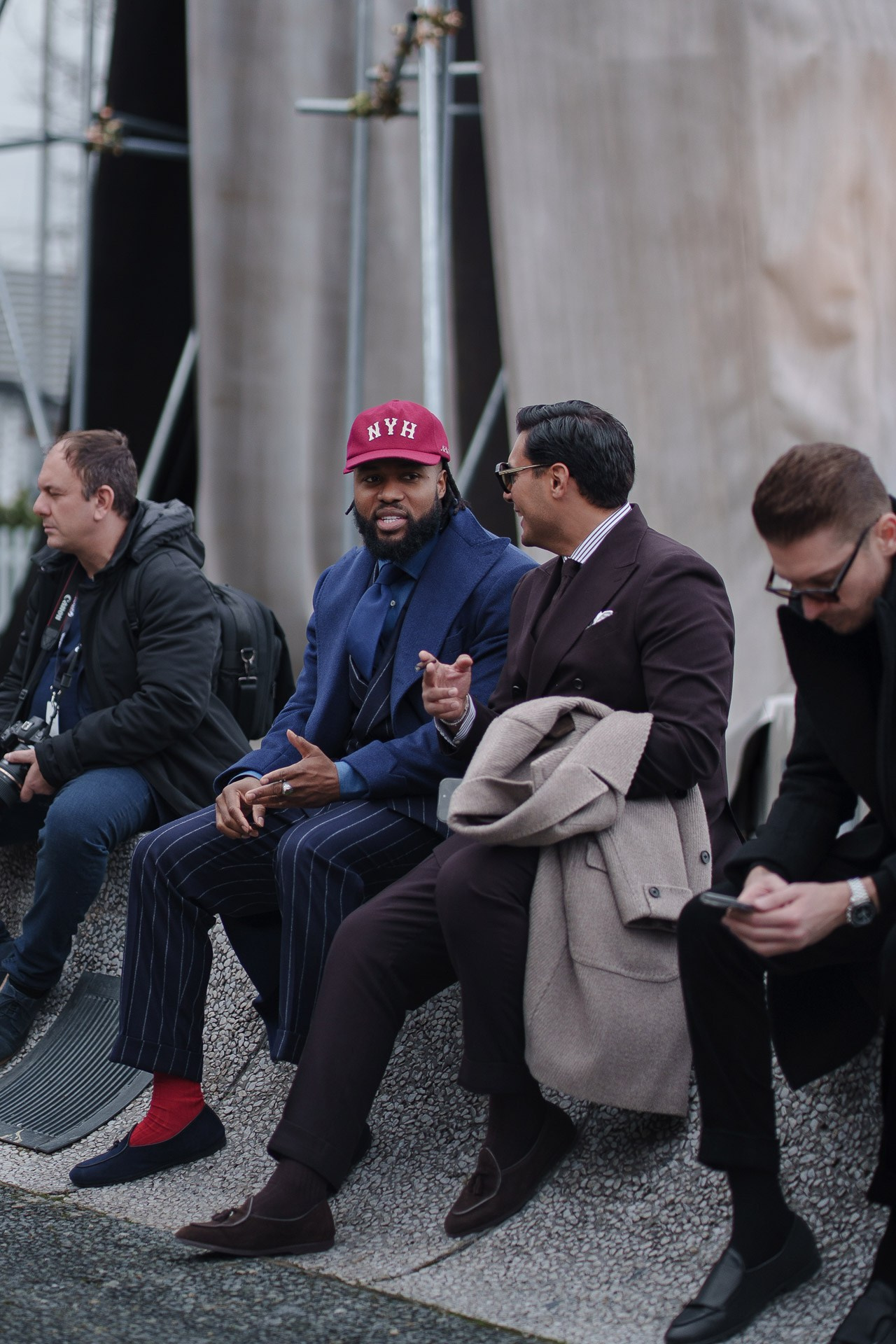 Group of men sitting and talking at Pitti Uomo Florence street style