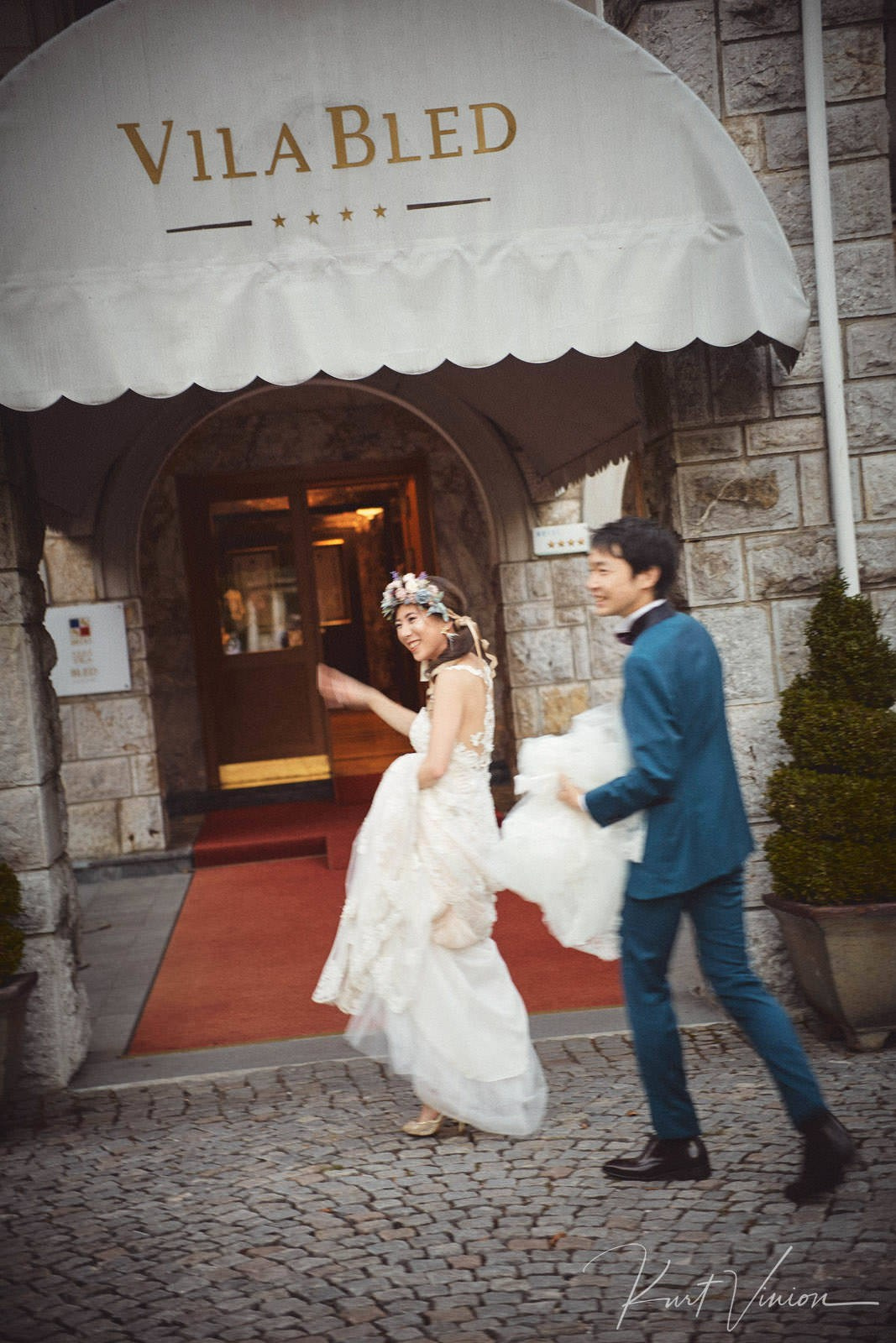 Happy Japanese newlyweds waving entering Vila Bled evening.