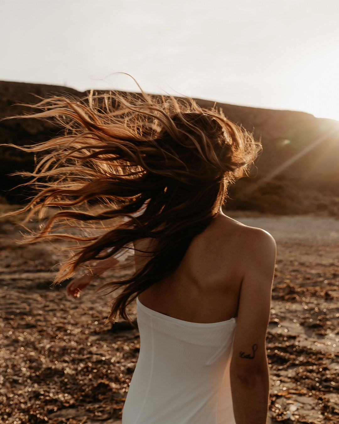 Retrato natural de Sandra con el pelo al viento en la playa.