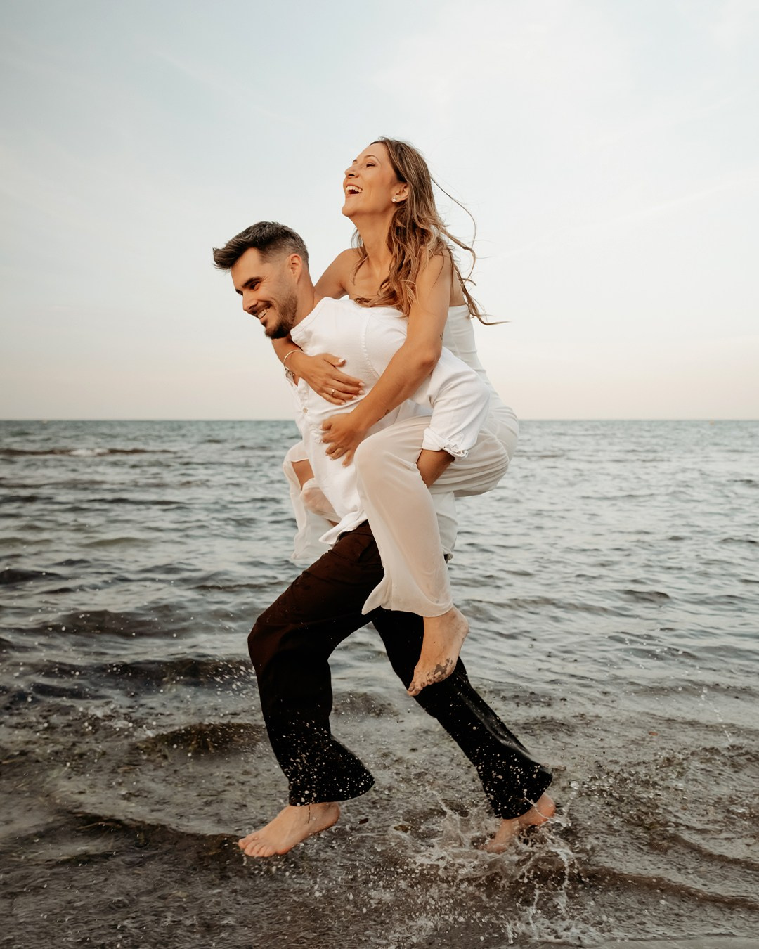 Pareja disfrutando de un momento divertido junto al agua del mar.