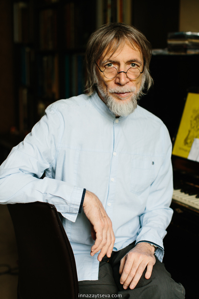 Vladimir Martunov, Porträt eines russischen Komponisten, der neben seinem Klavier sitzt und in die Kamera schaut