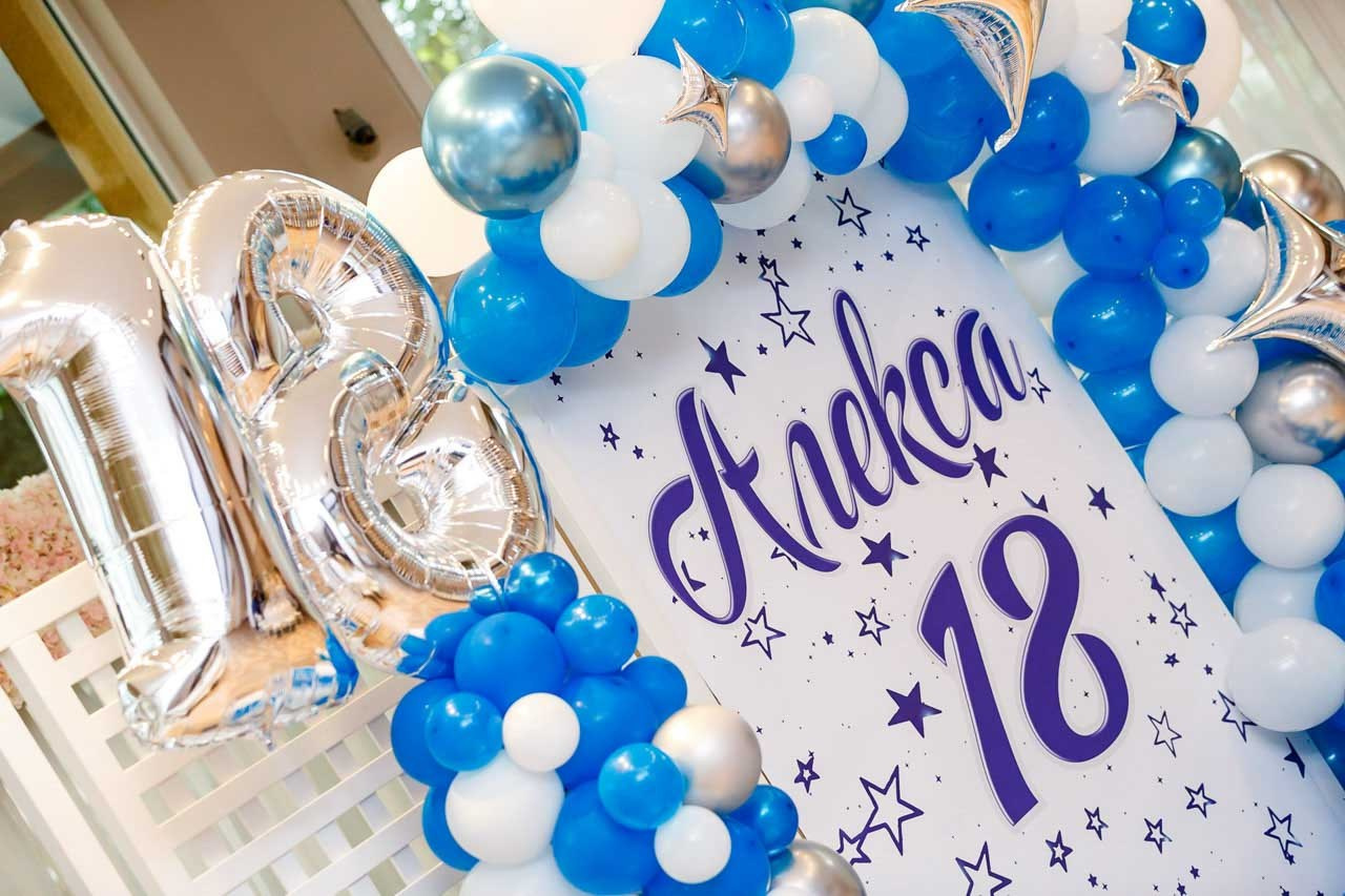 Dekoracija stola sa plavim detaljima i personalizovanim natpisom za 18. rođendan.