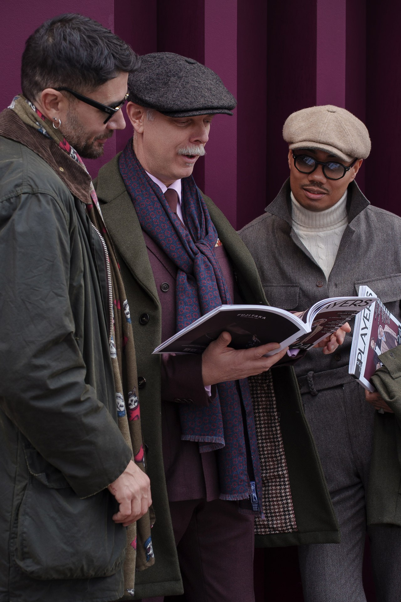 Men reading fashion magazine together during Pitti Uomo Florence