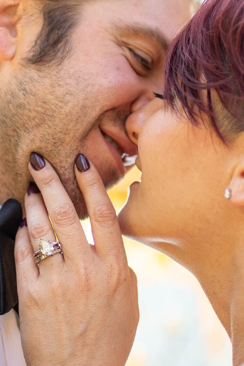 A close-up portrait of a bride and groom in an embrace with the focus on the diamond engagement ring.