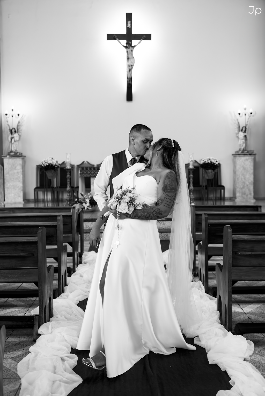 Foto em preto e branco dos noivos com as mãos unidas no seu casamento.