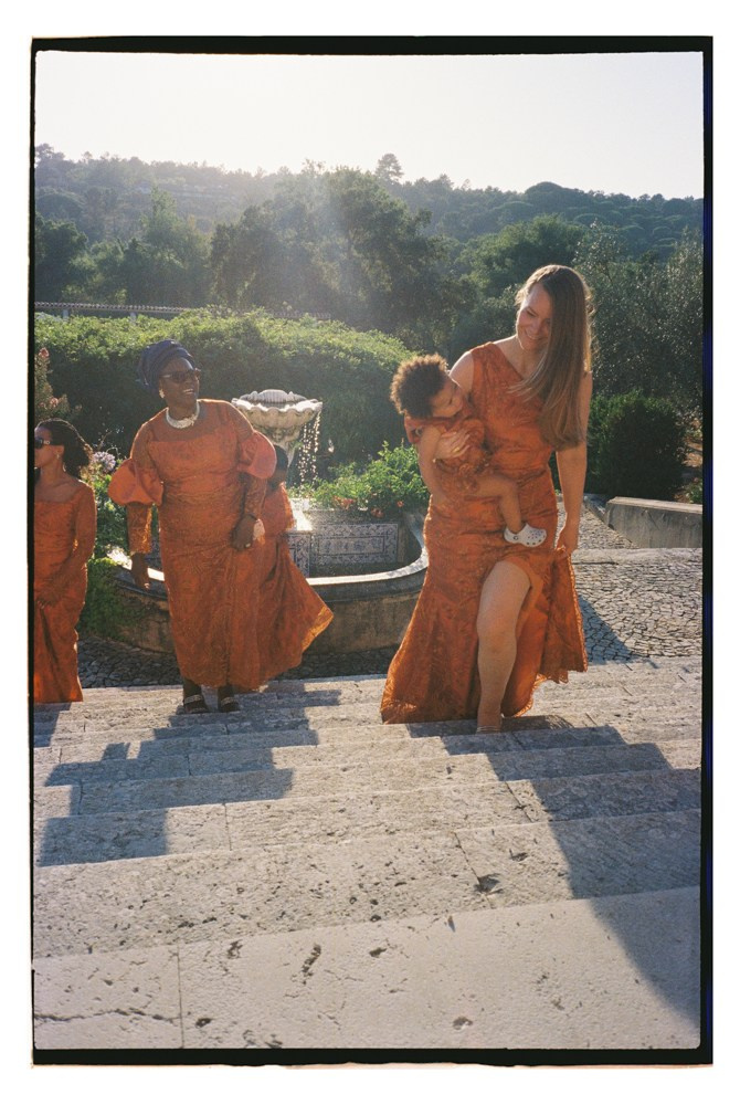 Women in orange attire walking upstairs during Nigerian wedding in Portugal