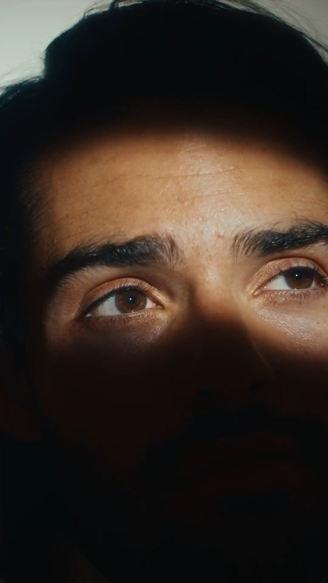 Close-up portrait of a male model in shadowy lighting, highlighting intense emotions.
