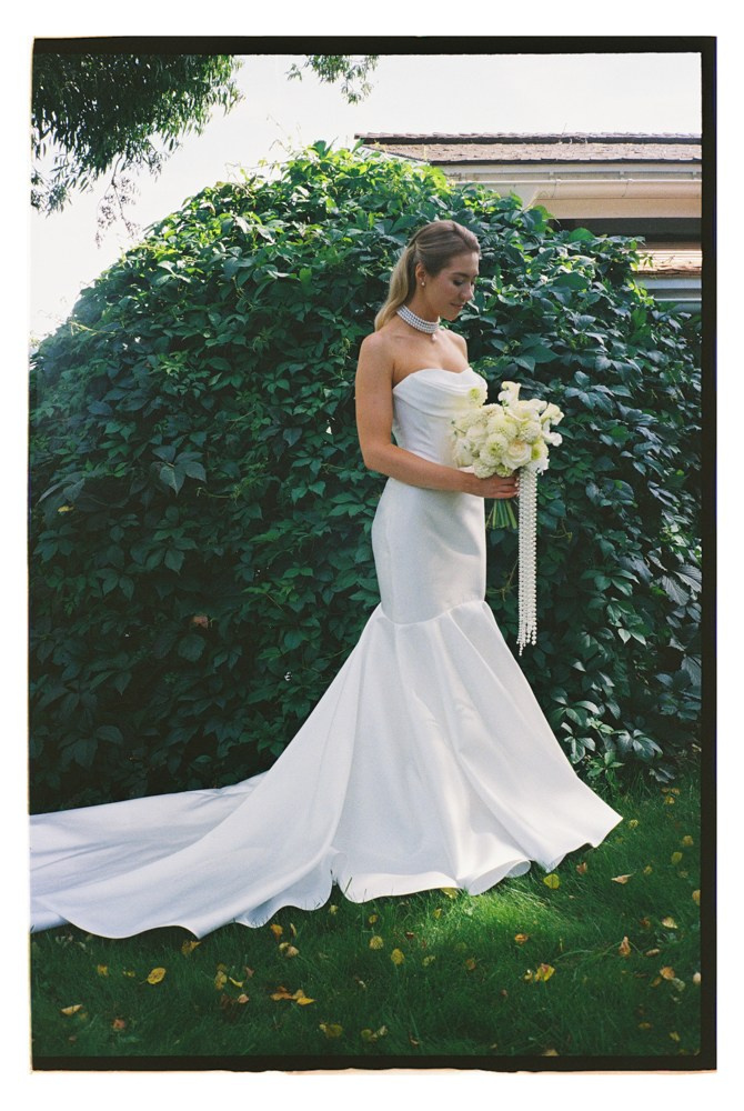 Bride holding bouquet beside greenery during editorial wedding portraits