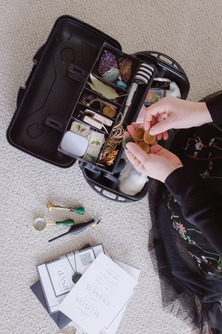 Hands of a woman over a box full of art supplies 