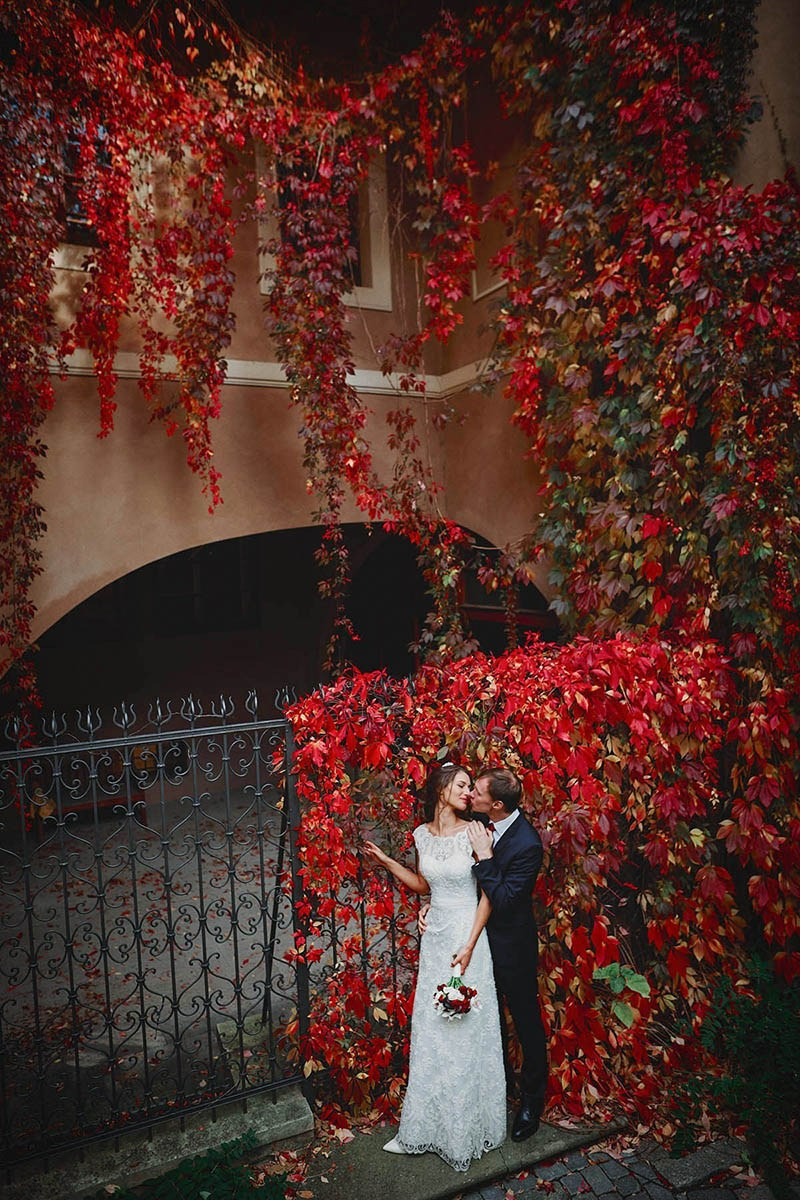 Couple embracing under red ivy in Ledebour Garden, Prague Castle wedding