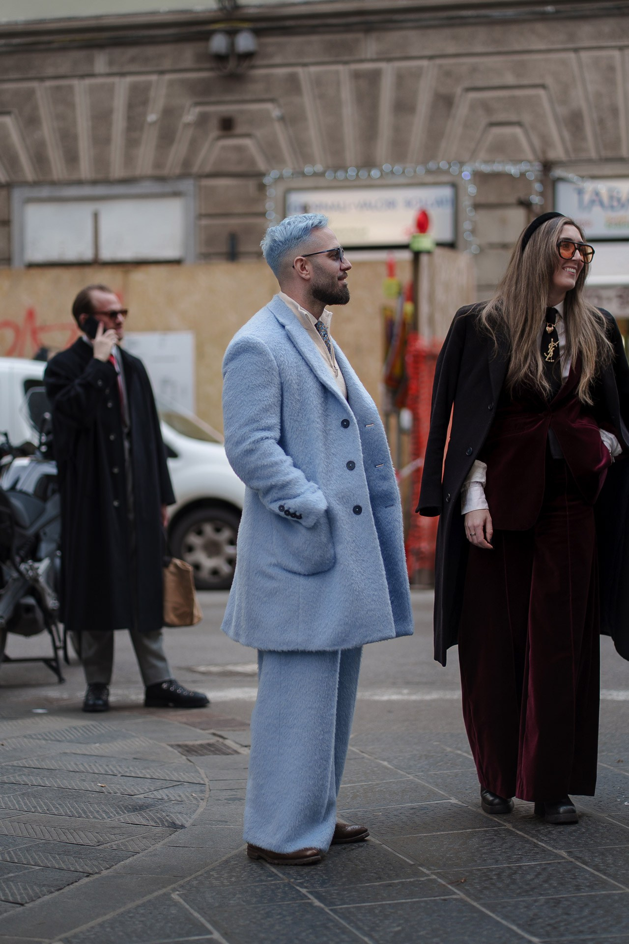 Stylish couple in pastel blue and burgundy outfits walking at Pitti Uomo 109 Florence street style