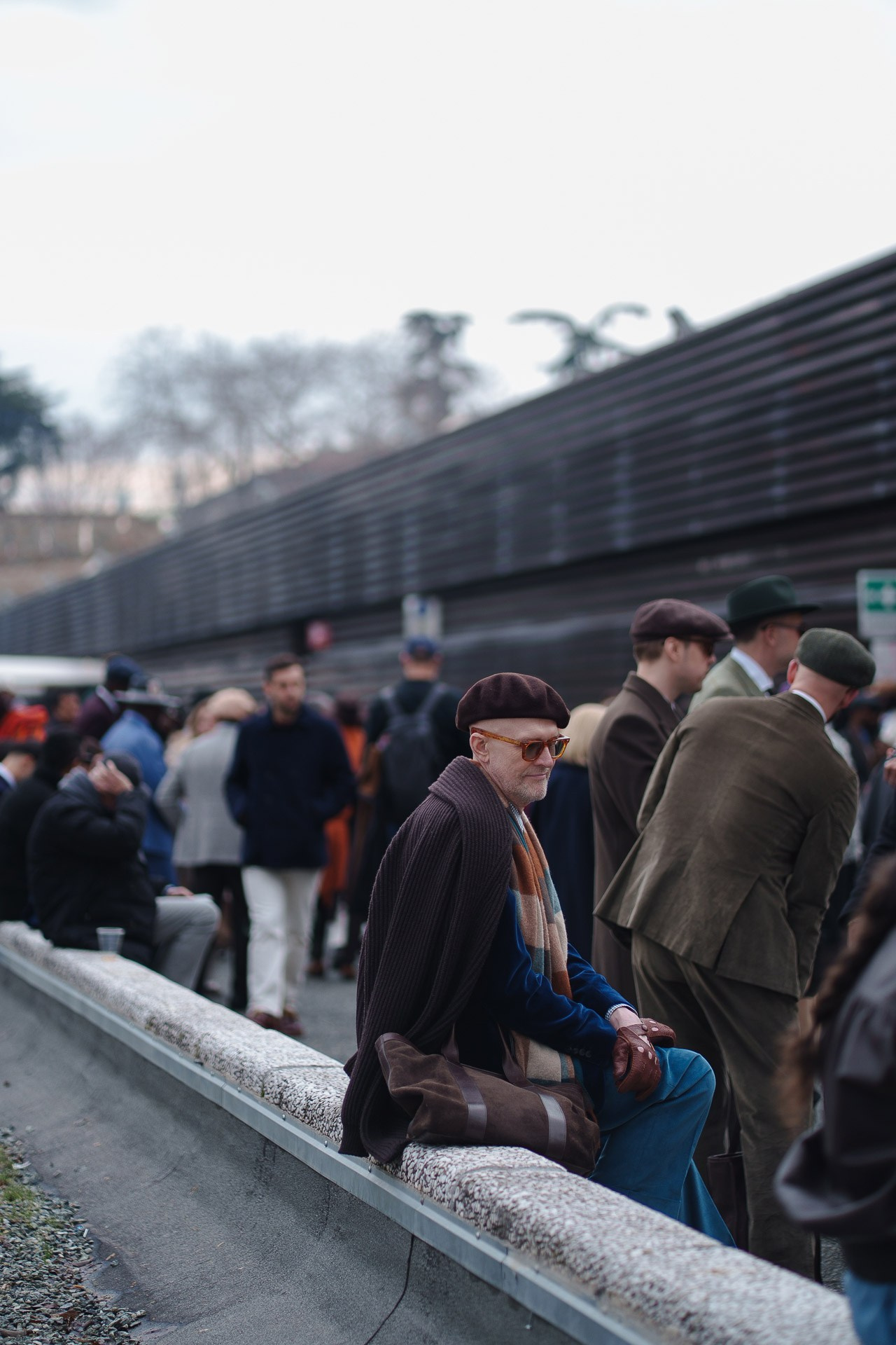 Men sitting and watching the crowd outside Pitti Uomo 109 Florence