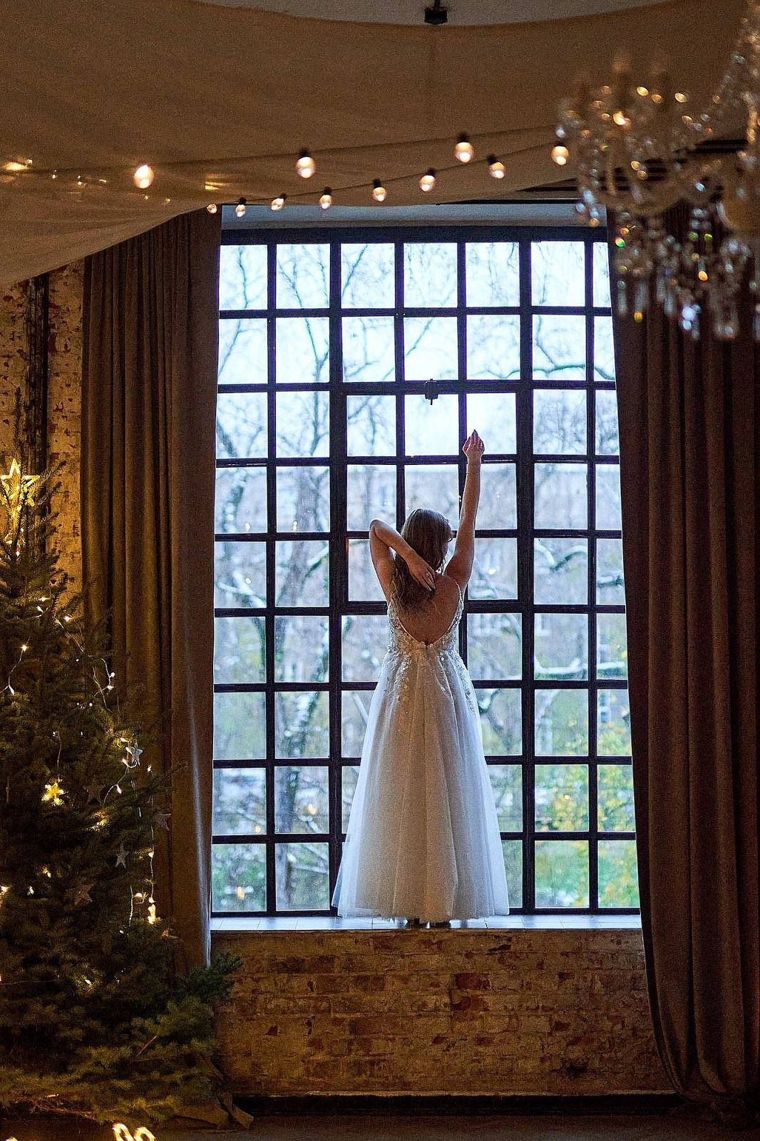 Detale ślubne: Suknia ślubna wyeksponowana przy dużym oknie w stylowym wnętrzu. Przygotowania do ślubu.