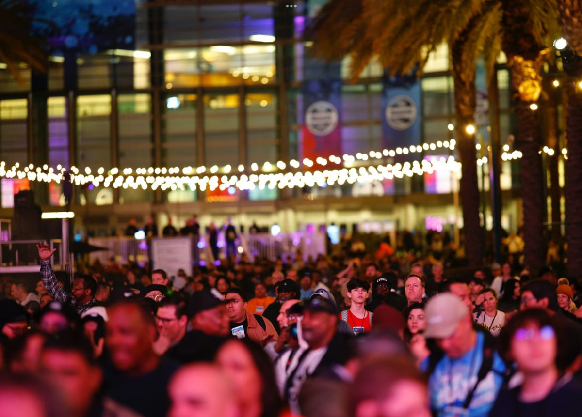 Large event crowd gathered beneath red stage lighting