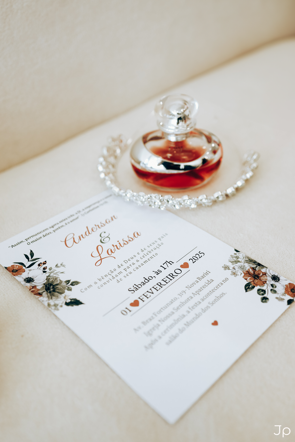  Composição de um perfume, uma coroa e um cartão sobre um sofá.