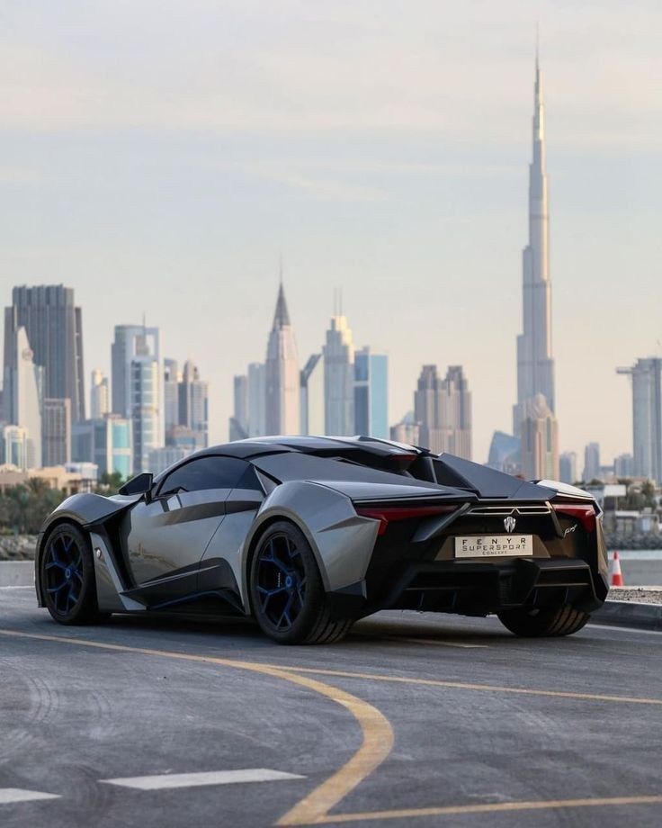 A grey Lamborghini on asphalt in Dubai with the Burj Khalifa and skyscrapers in the background.