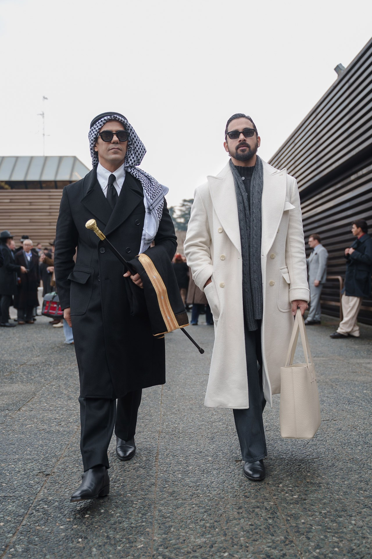 Two stylish men in long coats walking together at Pitti Uomo 109 Florence