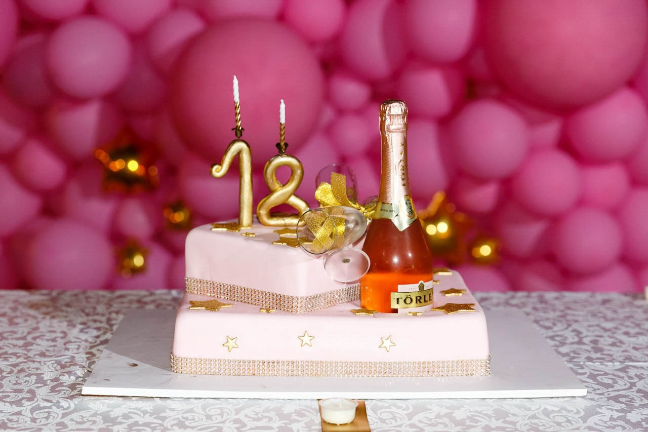 Detalj dekoracije stola sa rođendanskom tortom i šampanjcem za 18. rođendan.