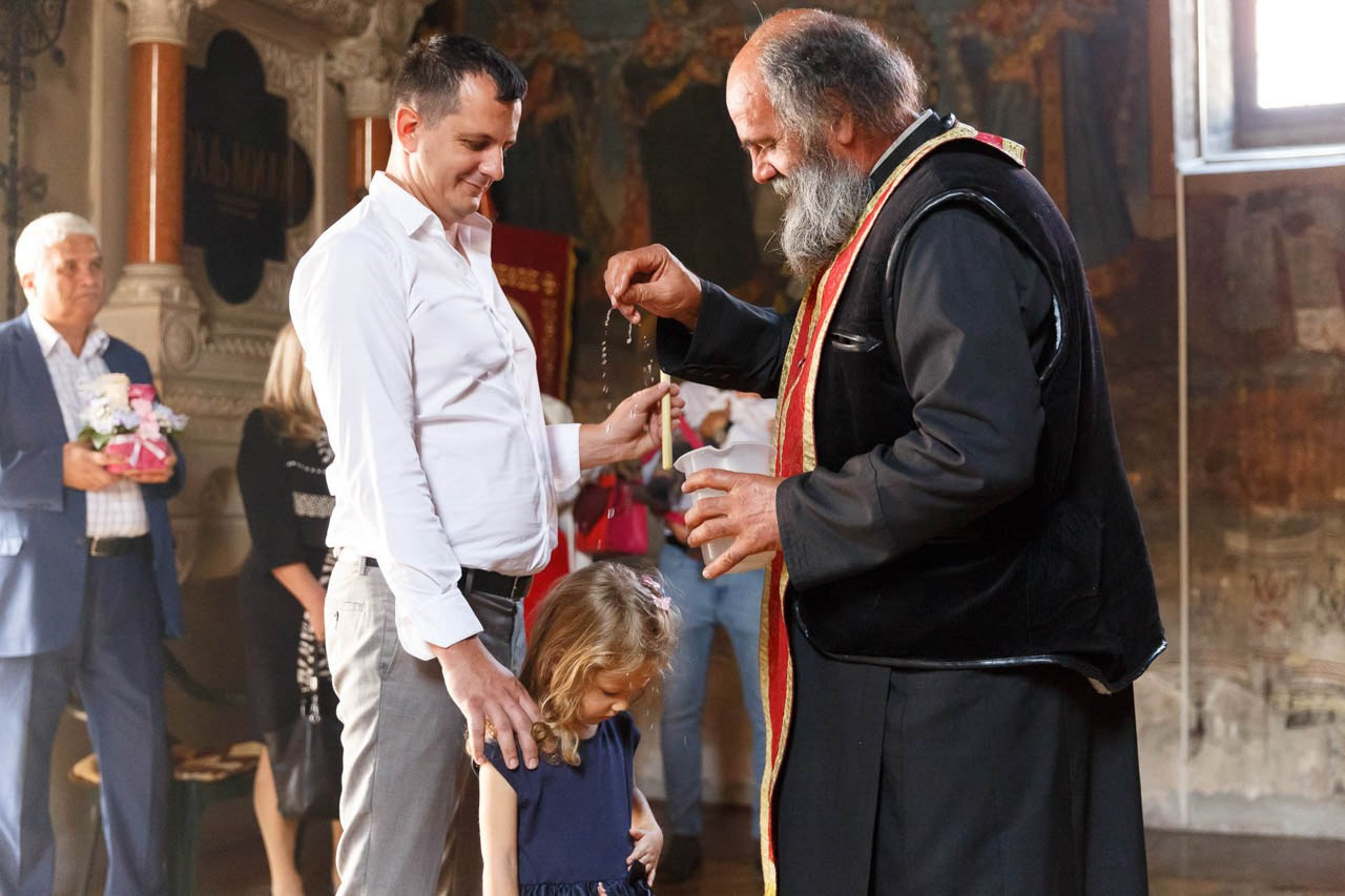 Svečani trenutak krštenja bebe u crkvi sa sveštenikom.