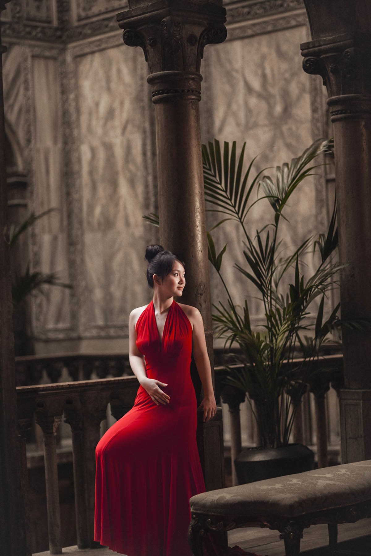 Thai woman in stylish red evening dress posing inside opulent Hotel Danieli in Venice.