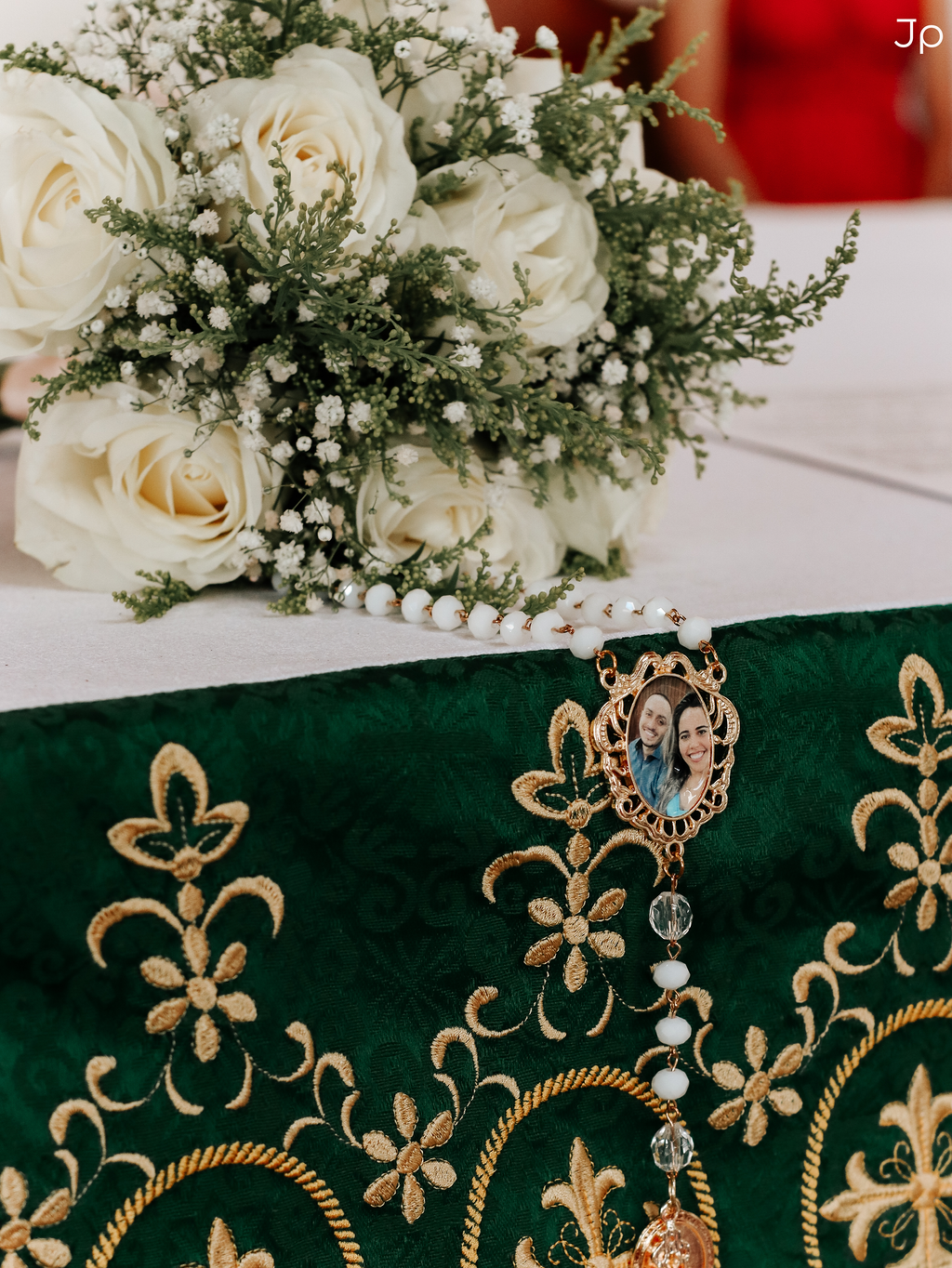 Detalhe do buquê da noiva sobre toalha verde com uma foto dos noivos.