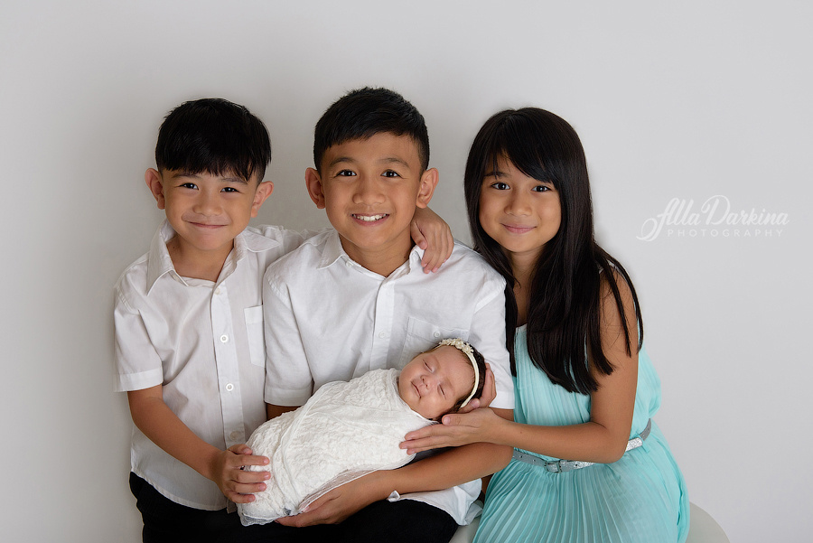 Loving siblings with newborn baby sister studio photo.