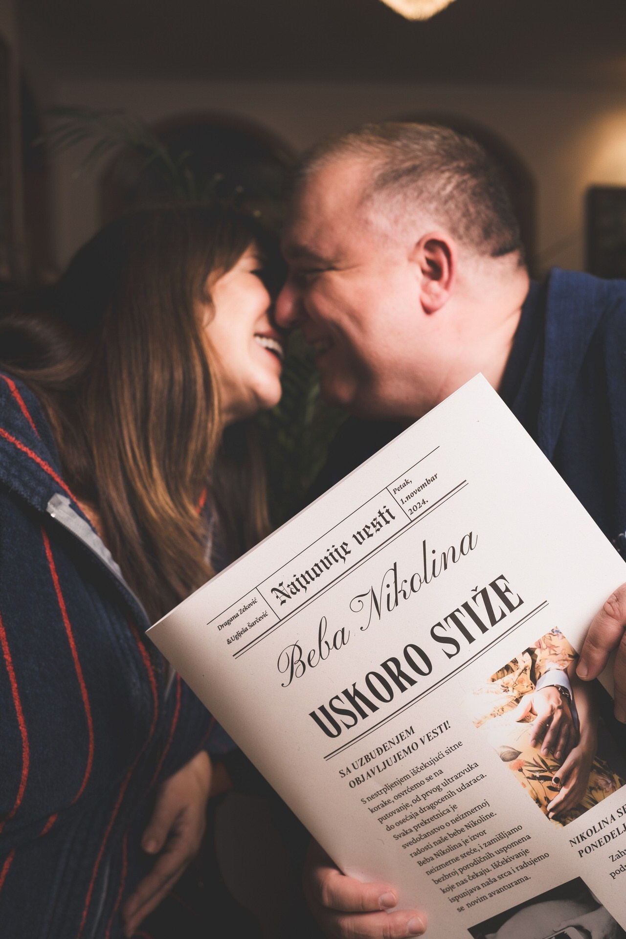 Nasmejani par se ljubi dok čitaju novine koje najavljuju skoro rođenje njihove bebe.