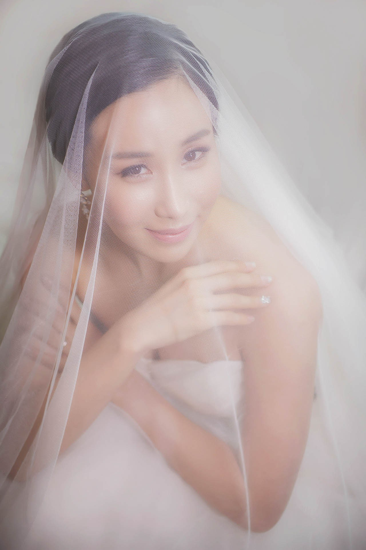 Elegant South Korean bride in designer dress posing underneath her veil.