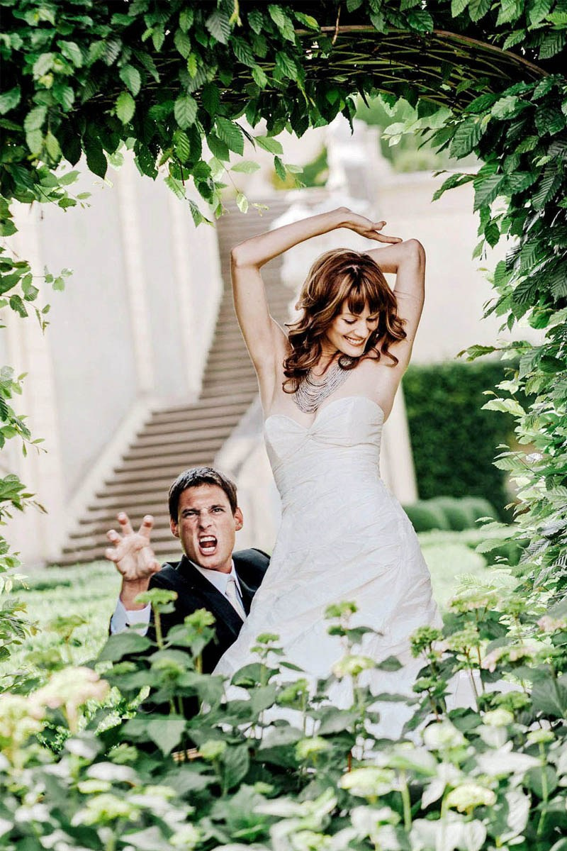 Groom making tiger gesture with red-haired bride posing in Vrtba Garden, Prague, destination wedding