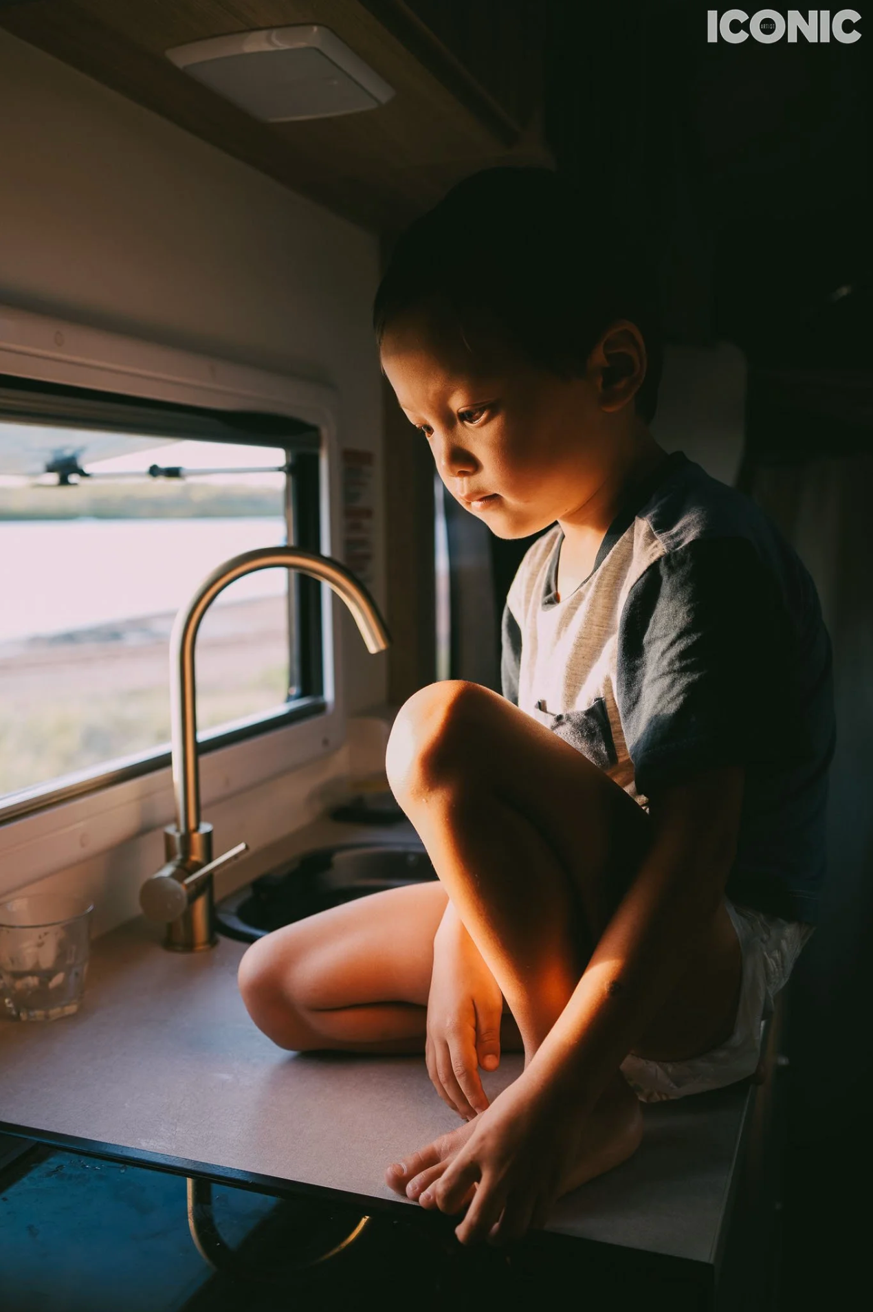 Child by a window bathed in natural light, thoughtful family portrait in Solihull.