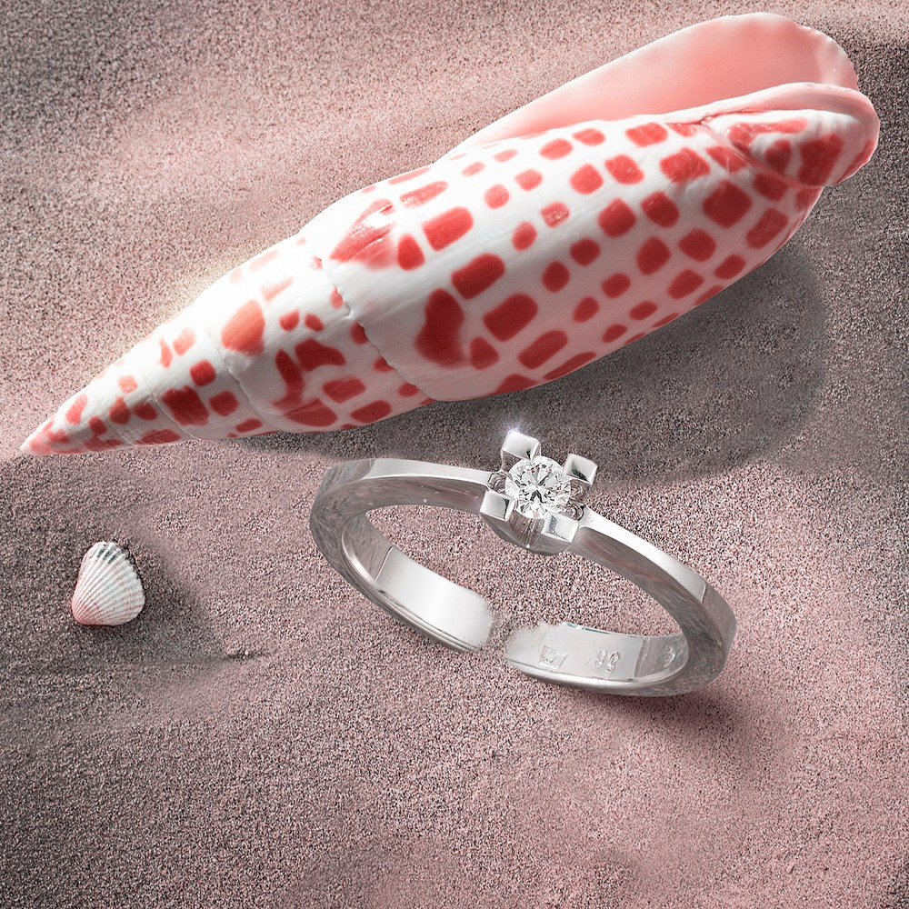 Zlatni prstena u pesku pored školjke.