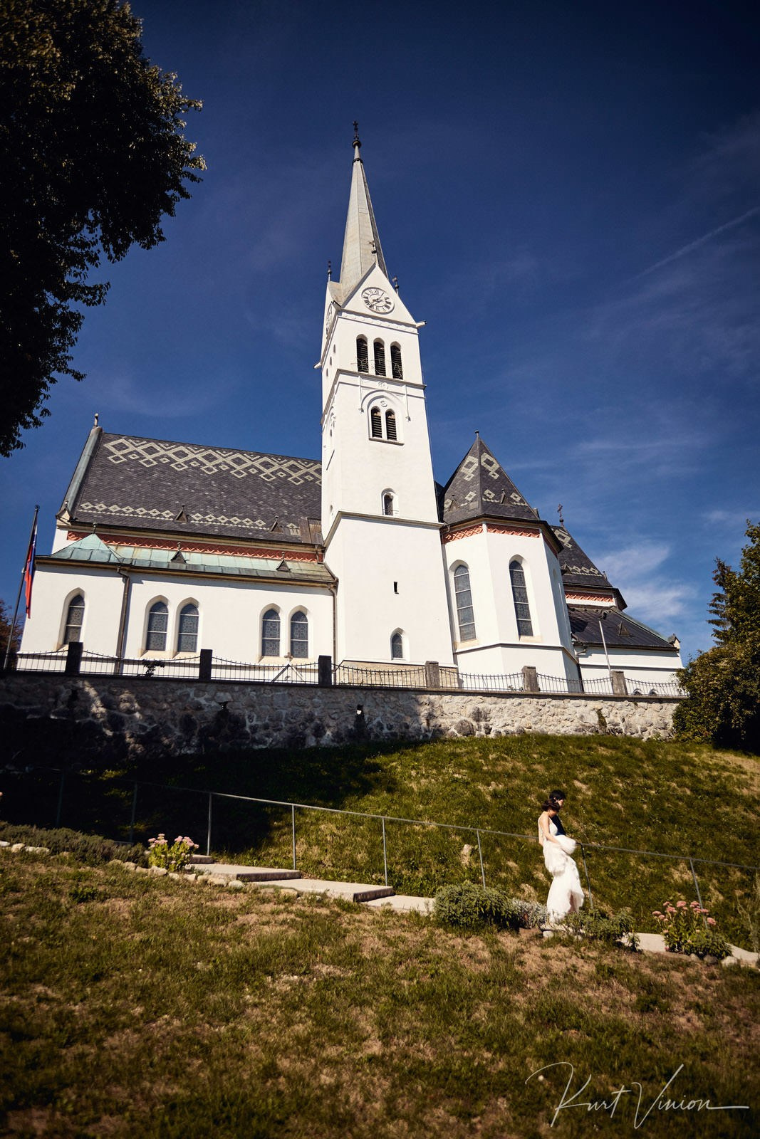Newlyweds walking down St Martin's Church steps white steeple background.