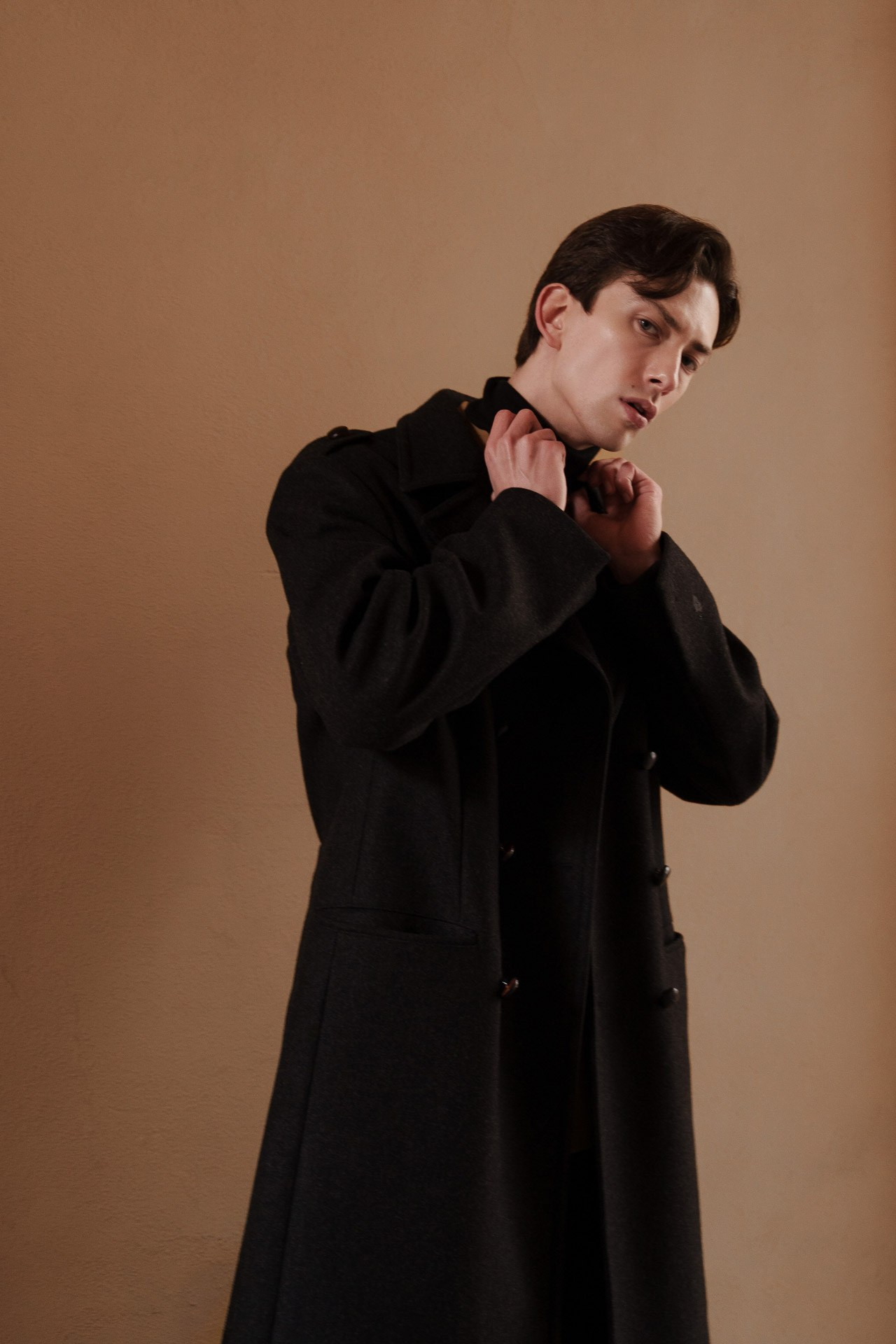 Male model adjusting coat collar during a portfolio shoot in Milan