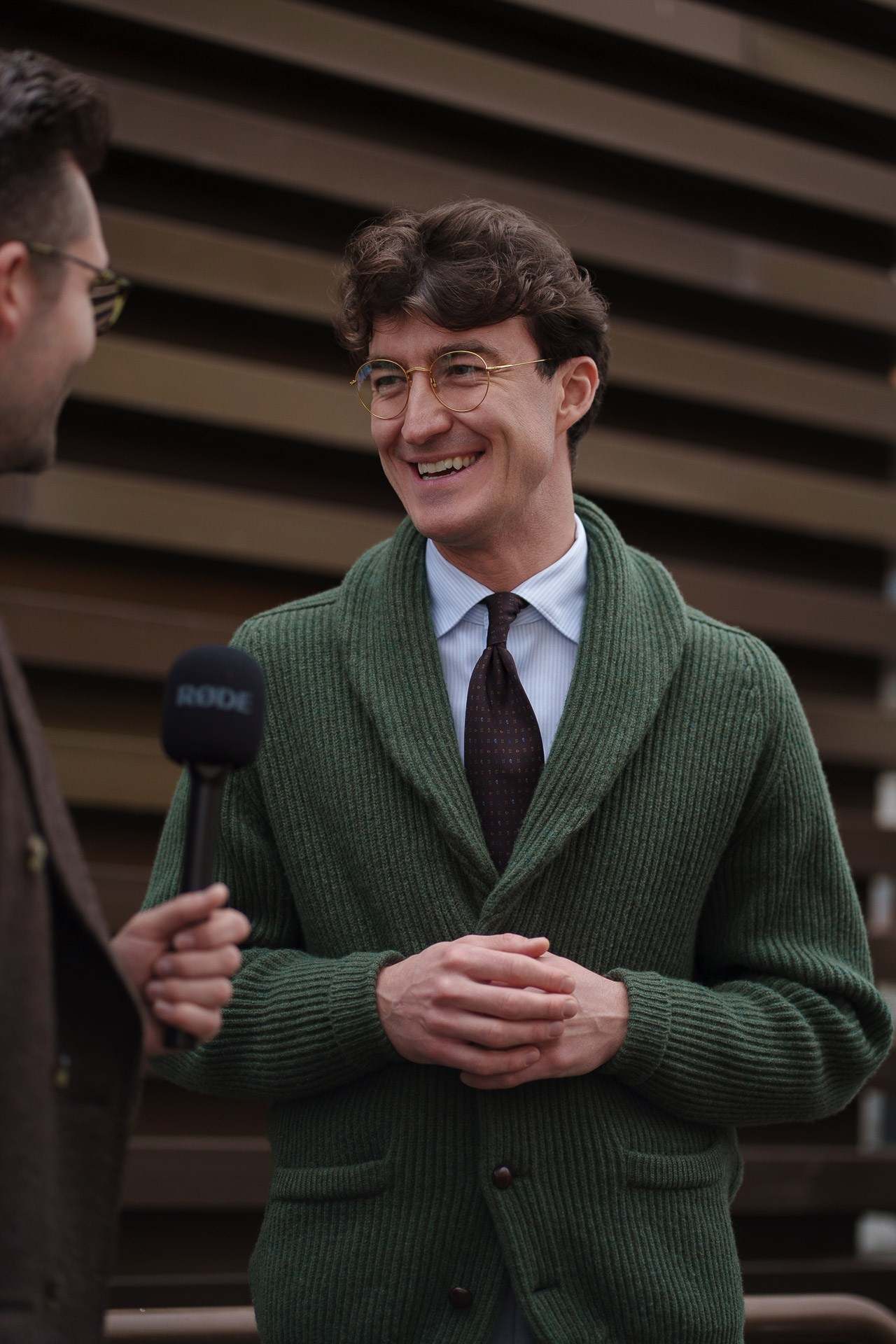 Man in green cardigan smiling during street style interview at Pitti Uomo