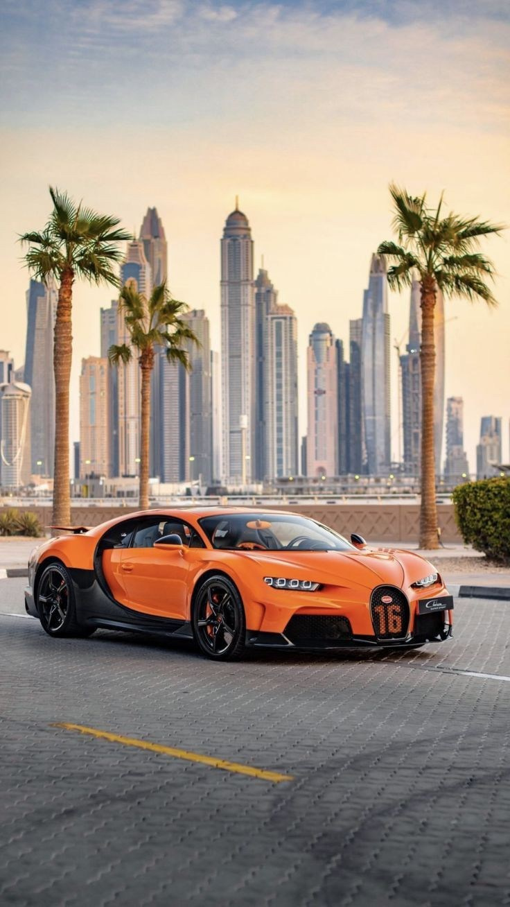 Orange Bugatti with Dubai Marina:“Orange Bugatti surrounded by palm trees and Dubai Marina skyscrapers under a warm sunset sky.”