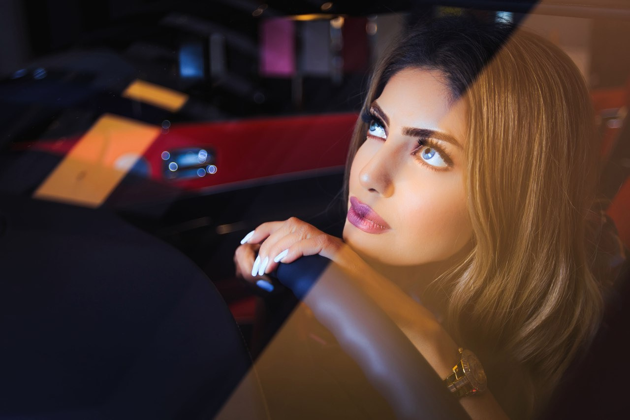 A girl with turquoise eyes gazes upwards from the interior of a car during a professional photoshoot.