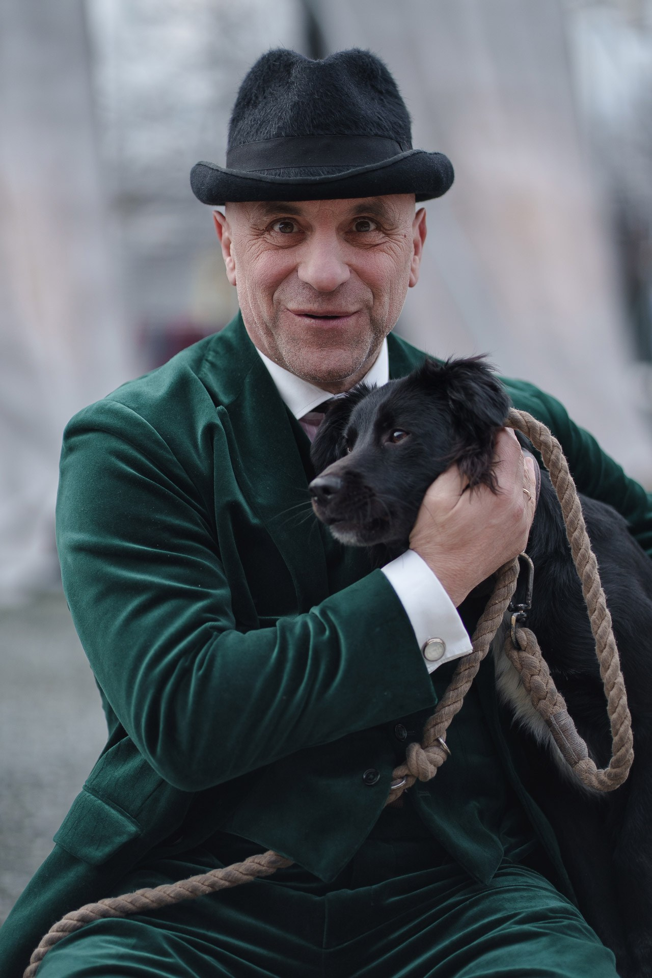 Man in green velvet suit posing with dog at Pitti Uomo street style