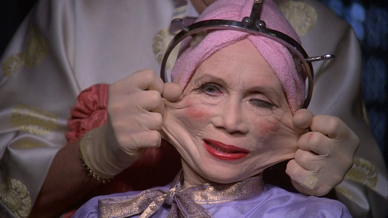 Терри Гиллиам, «Бразилия» 1985: антиутопия. Растянутое руками кожа лица ярко накрашена