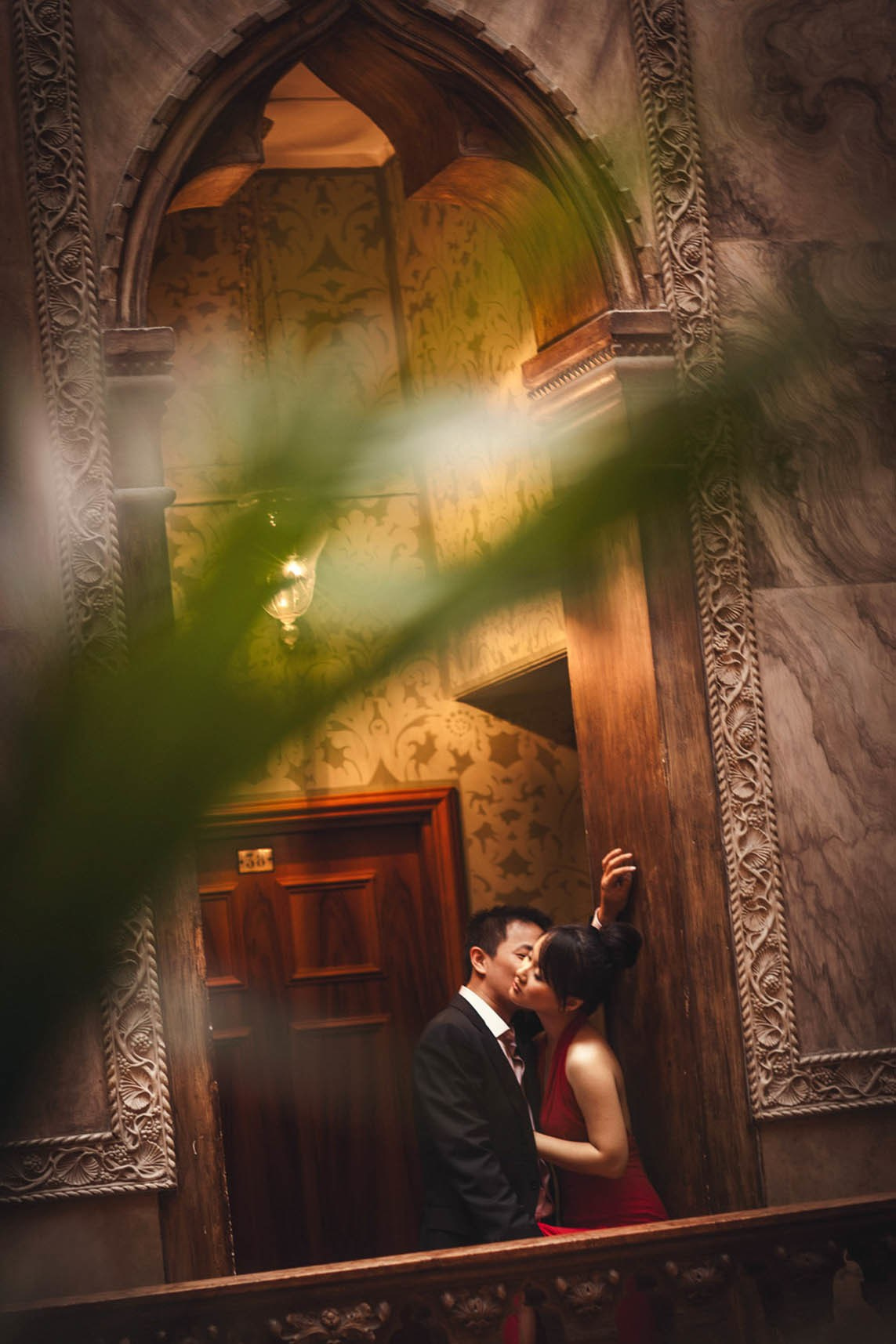 Thai man embracing partner in stylish red dress inside historic Hotel Danieli Venice.