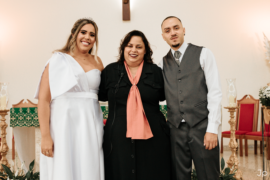 Noivos ao lado de uma celebrante sorridente em Bariri.
