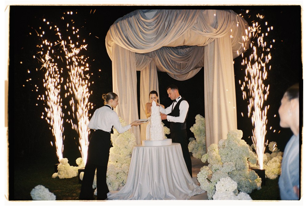 Couple cutting cake under canopy during luxury wedding reception