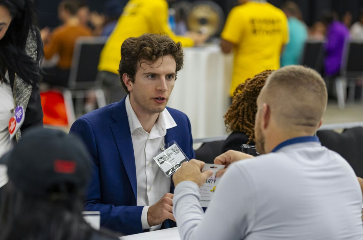 Interviewer speaking with an attendee on a busy trade show floor