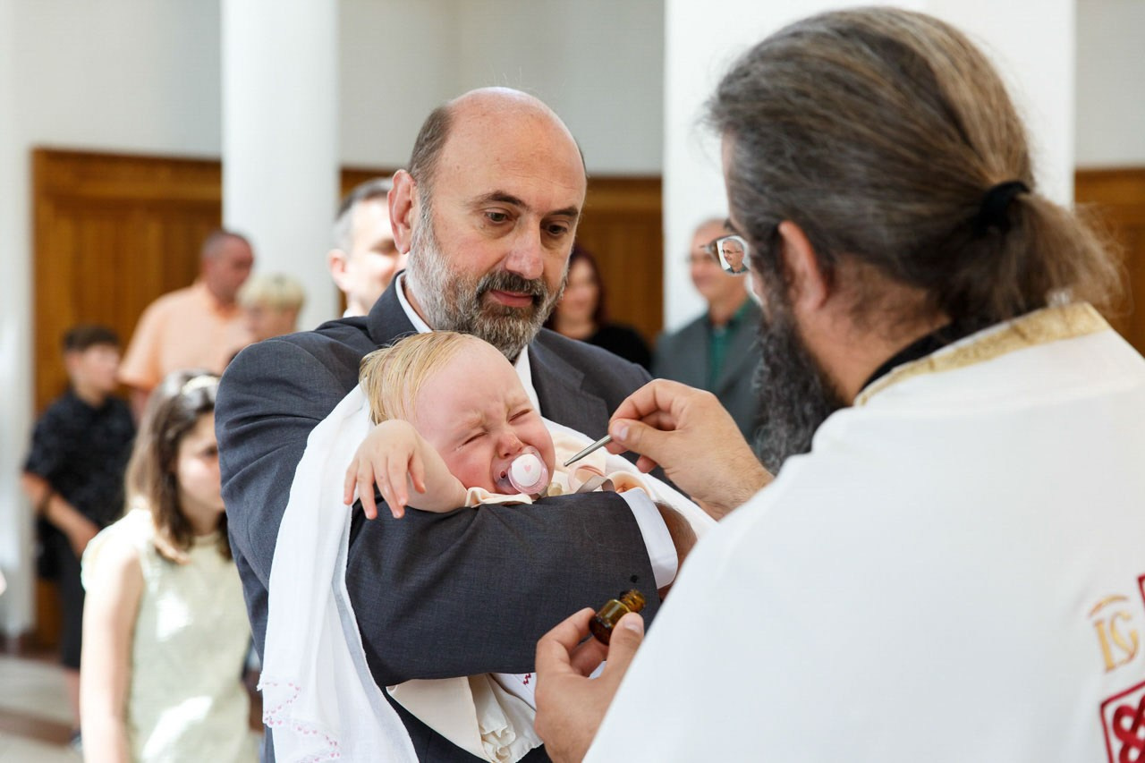 Trenutak kuma sa bebom tokom ceremonije krštenja.